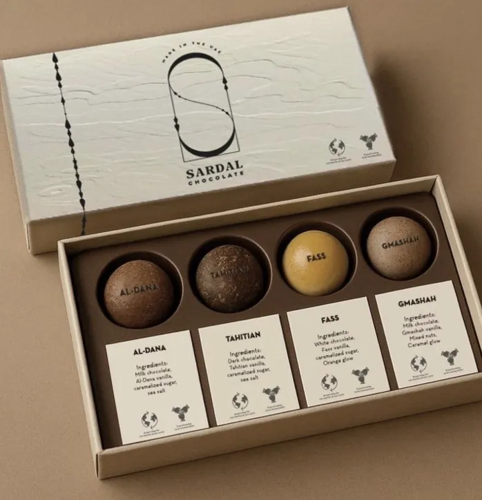 An open Sardal Chocolate Pearls gift box with four pearls, Al-Dana, Tahitian, Fass and Gmashah, each above its name card
